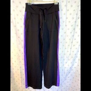 Lululemon black wide-leg draw-string pants with purple racing stripe.